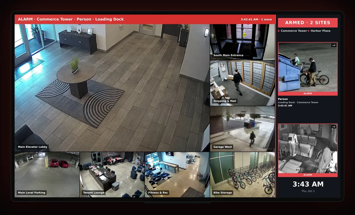 A TV showing a live camera wall with an alarm banner and alarm cards