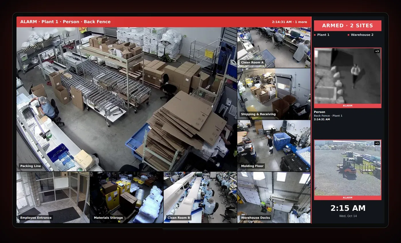 A TV showing a live camera wall with an alarm banner and alarm cards